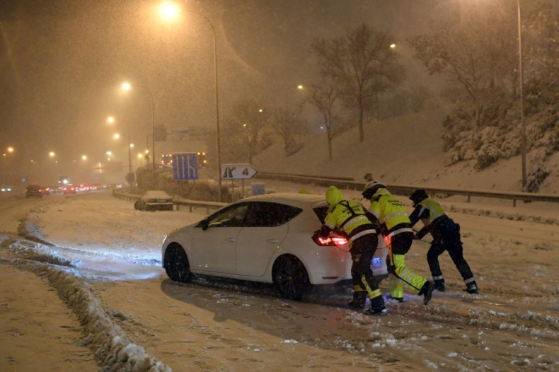Emergency services workers and soldiers freed 2,500 drivers trapped by the storm, which killed at least three people -- these firefighters helped push a vehicle stuck on Madrid's  M30 ringroad