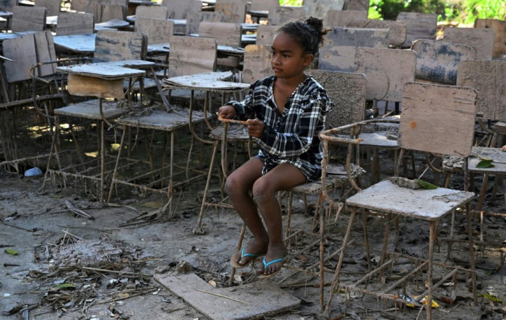 A little girl sits on a chair at a school that was destroyed by the Eta and Iota hurricanes