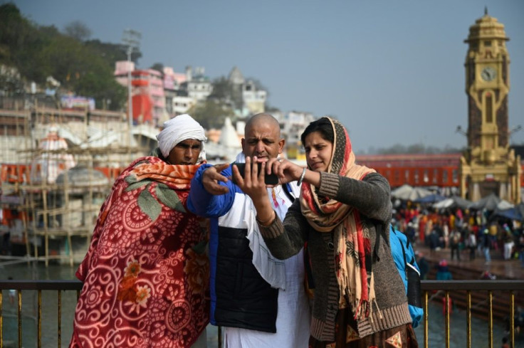 A family takes selfies on the banks of the Ganges