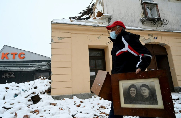 A man takes out old family pictures from a destroyed house