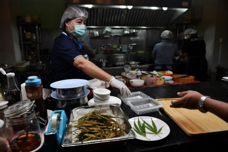 In the restaurant's bustling kitchen, a cook batters marijuana leaves and fries them to golden crispness, while another sprinkles them in a wok of minced meat with chili