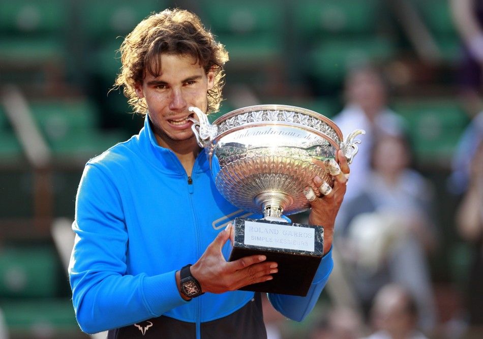 Nadal of Spain bites the trophy as he poses during a ceremony