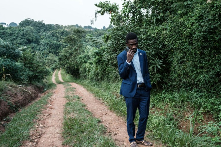 Presidential candidate Robert Kyagulanyi, also known as Bobi Wine, talks on the phone after talking to members of the media at one of his the gates of his home in Magere, Uganda, on Friday.