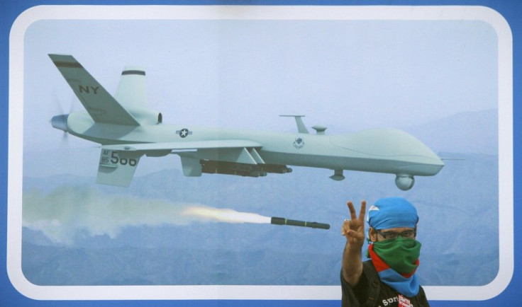 A supporter of religious and political party Jamaat-e-Islami flashes the victory sign in front of an image of drone, during a rally against drone attacks in Karachi