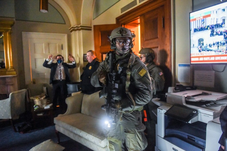 A Congress staffer holds his hands up while Capitol Police Swat team check everyone in the room as they secure the floor of Trump supporters in Washington, DC