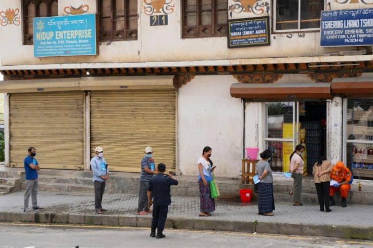 People in masks maintain social distancing as they queue to buy groceries in  Thimphu, Bhutan. The Himalayan kingdom says it will only start vaccinating citizens on an "auspicious" date