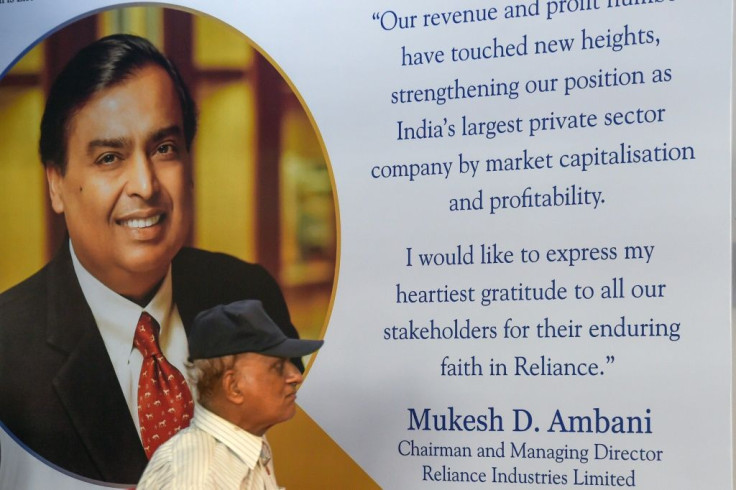 A shareholder walks past a poster of India's richest man Mukesh Ambani, whose Reliance Industries saw profits soar 12.5 percent in the last quarter of 2020