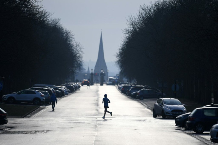 A jogger runs across a road in Greenwich Park in south east London on January 23, 2021. England has been in a third nationwide lockdown since early this month