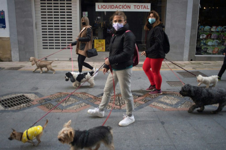 Women walk their dogs past a closed shop in central Ronda on January 22, 2021 as new coronavirus measures came into force in the Andalusia region in Spain