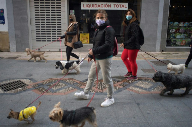 Women walk their dogs past a closed shop in central Ronda on January 22, 2021 as new coronavirus measures came into force in the Andalusia region in Spain