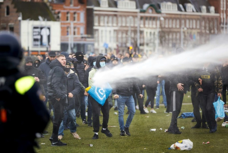 Demonstrators are sprayed by police water cannon at Amsterdam's Museumplein during a protest against virus lockdowns