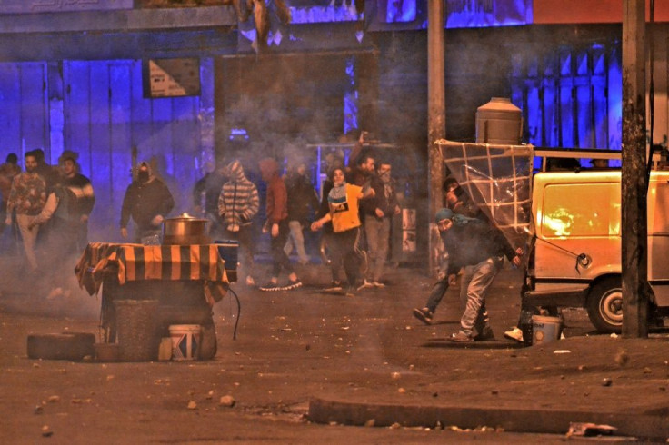 Anti-government protesters clash with security forces amid tear gas following a demonstration against dire economic conditions, in the northern Lebanese city of Tripoli on Monday