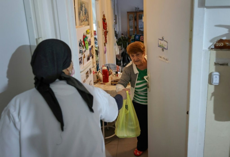Holocaust survivor Haya Caspi, an 88-year-old of Romanian origin who lost her parents during World War II, receives a food parcel from a volunteer on the premises of Israel's Yad Ezer La-Haver foundation