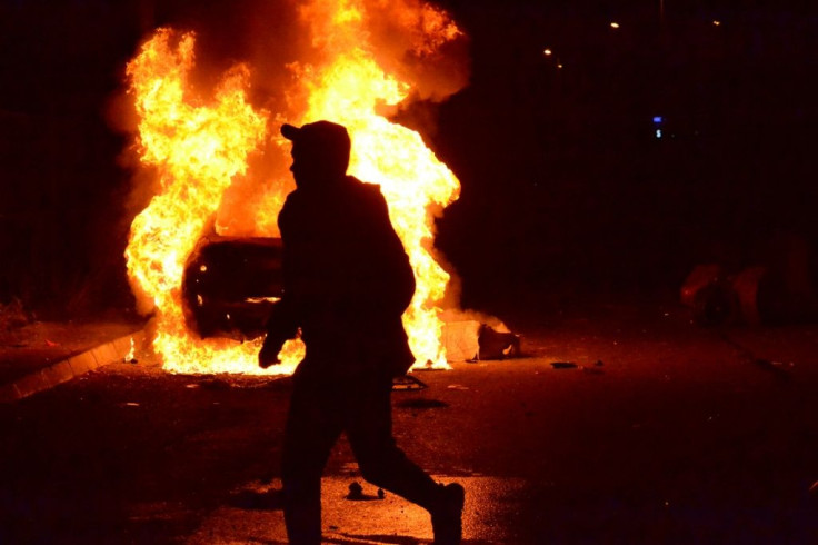 A protester runs past a burning vehicle during clashes with the army in Lebanon's impoverished second city Tripoli