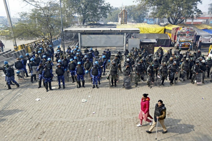 Security personnel stand guard along a blocked highway, as both sides dig in
