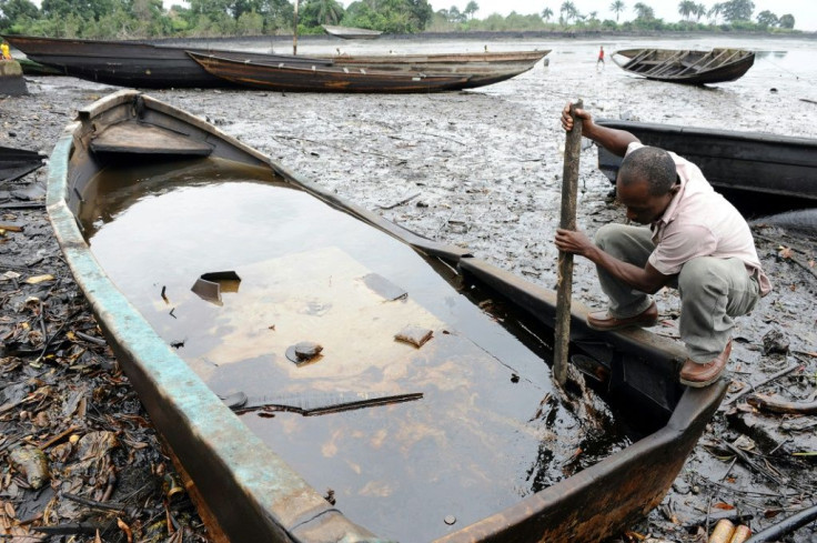 An man in Bodo, in the Ogoniland region, uses a stick to try to dig out crude oil from his boat. Local people said the oil spills devastated their livelihoods (2011 file picture)