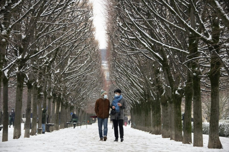 People wearing face masks walk on the Palais Royal grounds in Paris on January 16, 2021