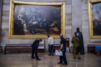Members of the office of the Architect of the US Capitol check for damage in the Rotunda in Washington, DC, on January 7, 2021, one day after the attack by pro-Trump extremists