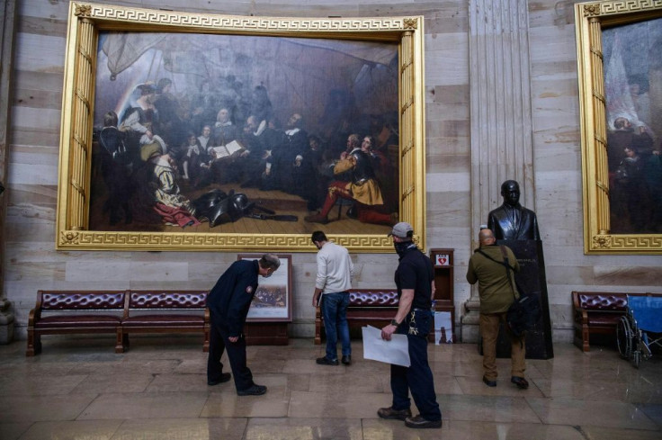 Members of the office of the Architect of the US Capitol check for damage in the Rotunda in Washington, DC, on January 7, 2021, one day after the attack by pro-Trump extremists