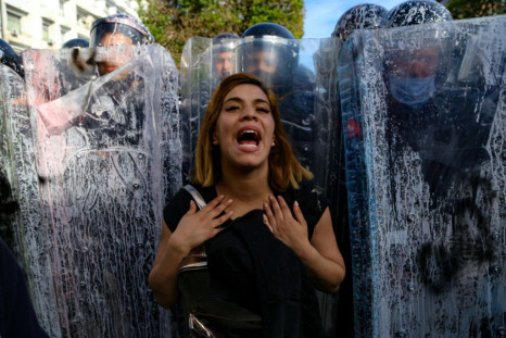 A Tunisian woman taking part in a demonstration in the capital Tunis on Saturday stands in front of police officers blocking access to the interior ministry