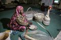 Halima Mohamed, a resident who returned to the Libyan city of Tawergha, sits making traditional palm products