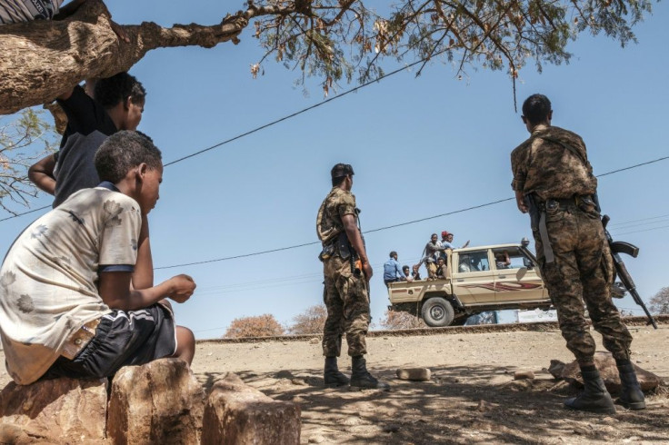 Ethiopian troops watch as a pick-up truck with militia men passes by the camp