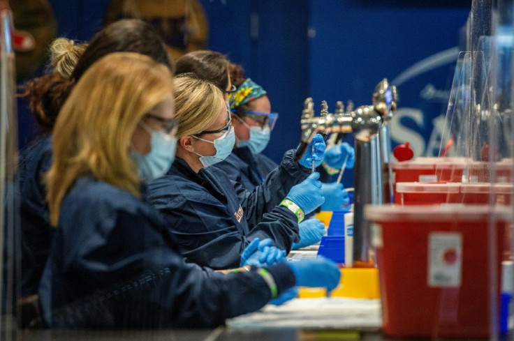 Medical staff workers prepare syringes with doses of Covid-19 vaccine while working behind beer taps at Fenway Park in Boston, Massachusetts