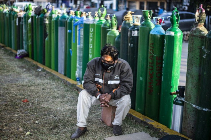 People brave the night chill, taking cover in small tents, under blankets or sheets of cardboard outside Criogas, a small oxygen factory in the port city of El Callao near the capital Lima
