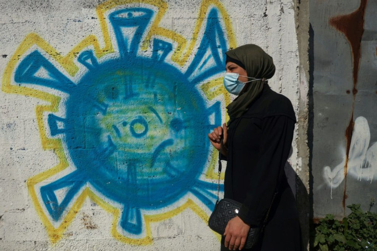 Tahani al-Rifi walks past a coronavirus-inspired mural in Gaza; one of some 7,000 Gazans who are currently diagnosed with cancer - but only about 100 of them are expecting permission to cross into Israel to access treatment