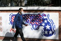 A man walks past a mural painted on the outer walls of the former US embassy in Tehran