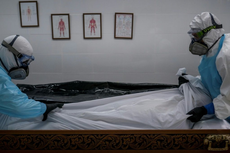 Staff in protective gear place the body of a Covid victim into a casket