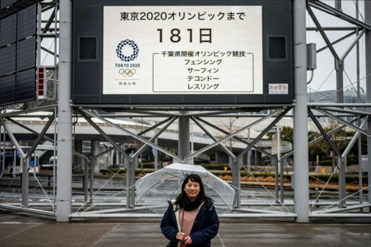Tarumi posing in front of an Olympic countdown clock, fears the Games' message of hope and equality could be lost