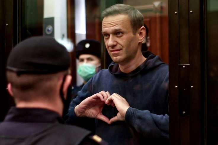 Navalny gestures a heart shape from inside a glass cell during a court hearing in Moscow