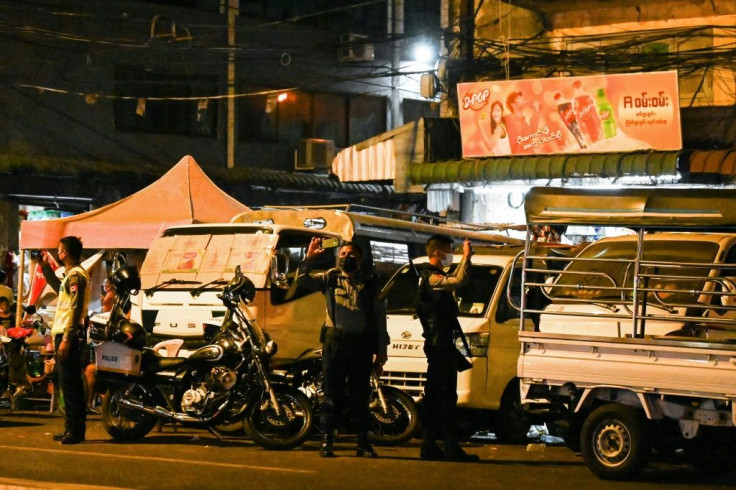 Police in Yangon use their phones to film people banging items in protest over the military coup