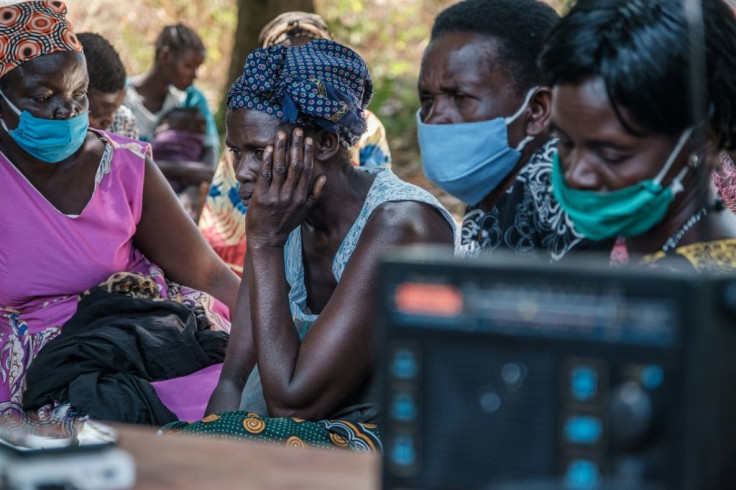 People from Lukodi gather around the radio to listen to the verdict