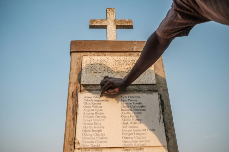 Olanyia Mohammed, 38, escaped a massacre in his village but lost 15 members of his family. He  points at his parents names etched on a memorial