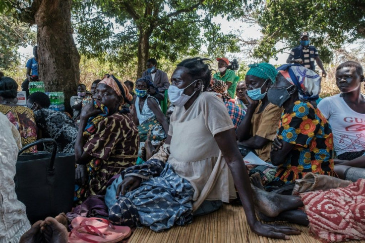 People from Lukodi gather around a radio to listen to the verdict