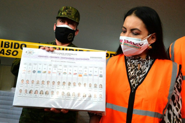 The president of the Electoral National Council of Ecuador, Diana Atamaint (R), shows the ballot paper for the upcoming Ecuadorean presidential election