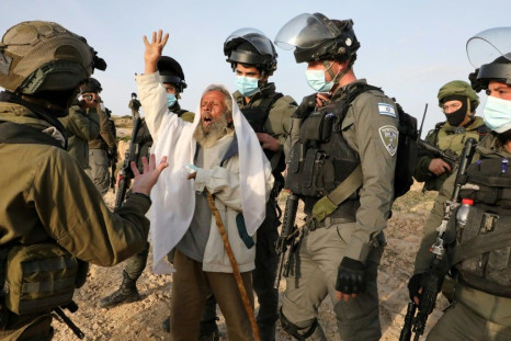 An elderly Palestinian man scuffles with Israeli security forces as he protests the removal by an army bulldozer of a temporary health unit in the village of al-Mufagara, near Yatta, south of the West Bank city of Hebron, in January