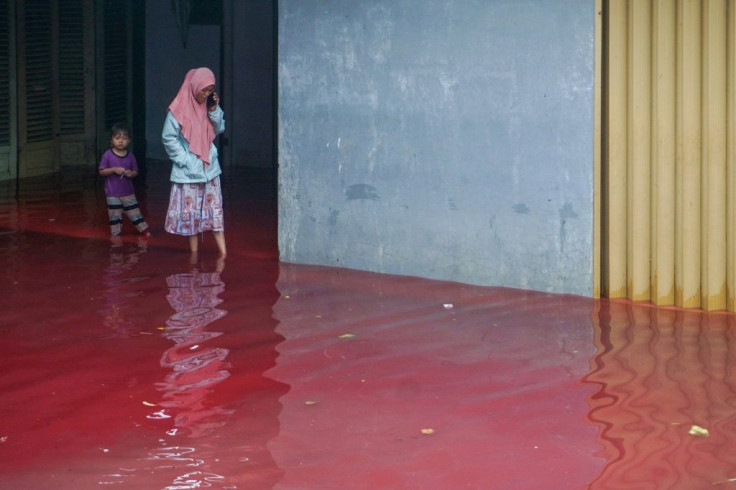 Residents waded through the blood-red floodwaters