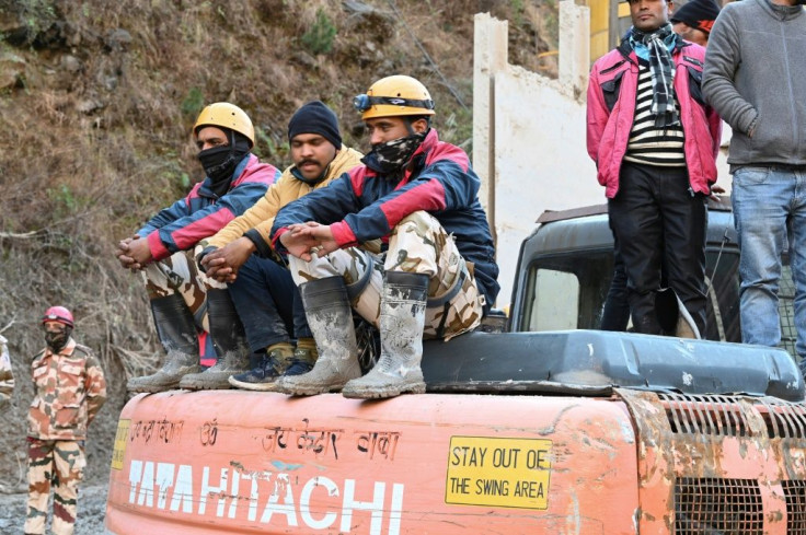 Rescue personnel rest on an excavator outside a tunnel blocked with debris during rescue operations in Tapovan of Chamoli district on February 8