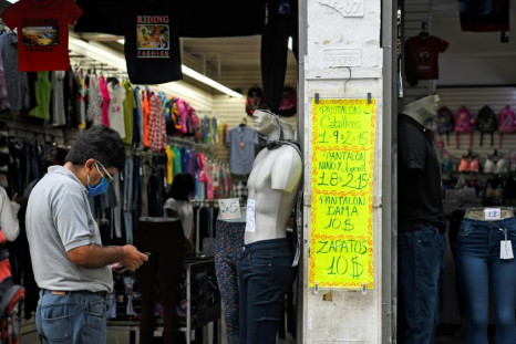 A man uses a mobile phone in front of a sign displaying prices in US dollars in December 2020 outside a clothing store in Venezuela's capital Caracas, which has been ravaged by hyperinflation and other economic problems