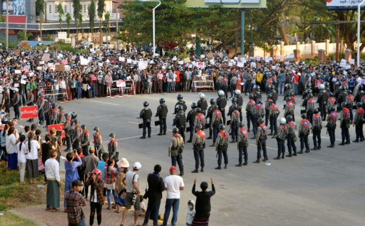 Protesters face off with police standing guard on a road during a demostration against the military coup in Naypyidaw on February 8