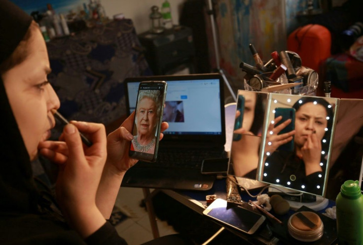 Jordanian make-up artist Alaa Bliha, 27, uses a portrait of Queen Elizabeth II saved on her mobile telephone to work on her imitation make-up