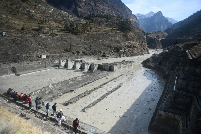 People look at the remains of a dam along a river in Tapovan of Chamoli district, destroyed after a flash flood thought to have been caused when a glacier burst