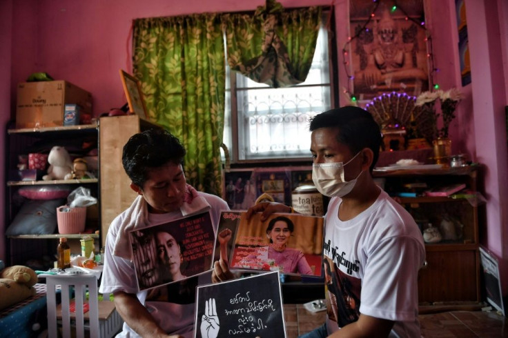 Myanmar shopkeeper and expat Kyaw Thu Ya (R) chooses signs to bring to a local protest against the military coup in his home country, at a house in the outskirts of Bangkok