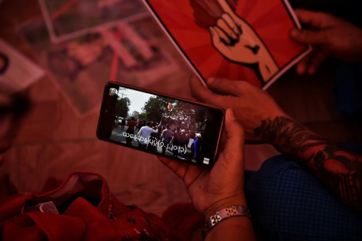 Myanmar migrants in Bangkok watch footage of mass protests in Yangon, as they gather together before going to a protest against the military coup back home