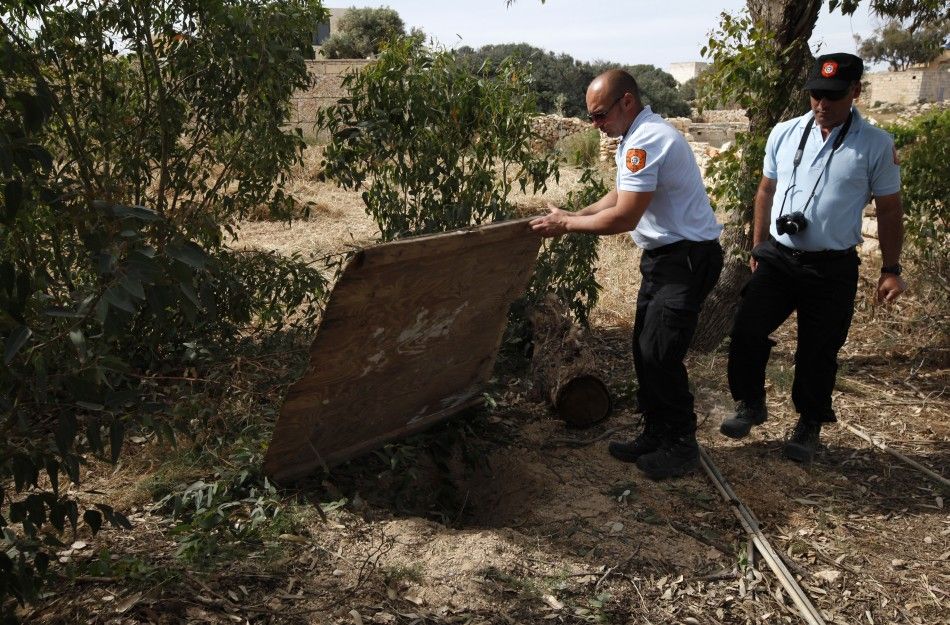 Animal welfare officers show the hole in the ground where they found a dog buried alive in a field near Birzebbuga in the south of Malta