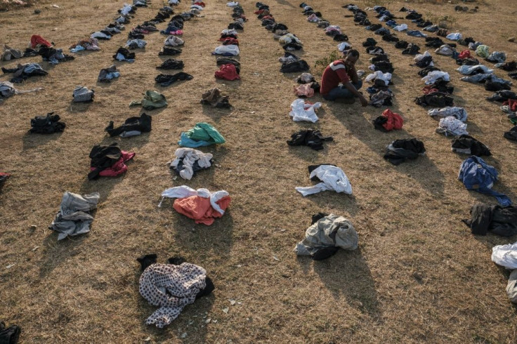 A displaced person sits among piles of clothes being distributed at the camp in Chagni