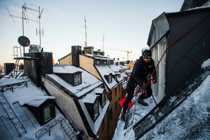 Rooftop snow remover Andrei Plian works on top of one of Stockholm's old town buildings. 'Being here on the roof and looking up at the sky, you feel that freedom,' he said